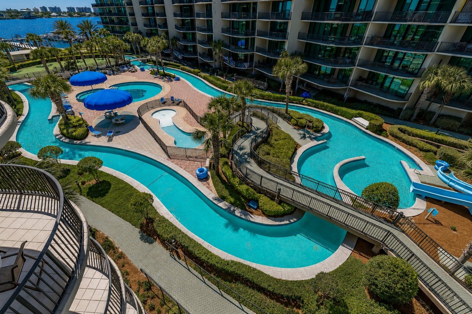 A resort with multiple swimming pools, a water slide, and a view of the ocean.