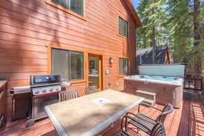 An outdoor deck with a grill, hot tub, and a table with chairs. - Tahoe Park Lodge 4 Bedroom Home (Tahoe City)