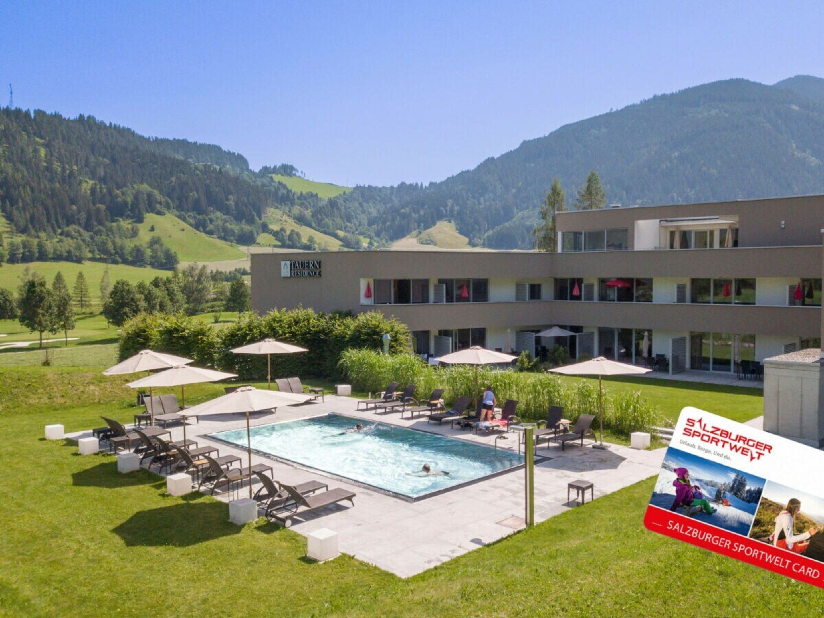 A hotel with a swimming pool, outdoor seating, and a view of the mountains.