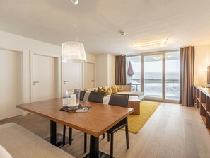 A modern hotel room with a dining area, a sofa, and a view of the sea. - Superior Holiday Apartment & Summer Pool (Radstadt)