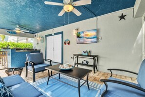 An outdoor patio with seating, a table, a ceiling fan, and a wall-mounted TV. - Blue Star Oasis by Duncan Real Estate (Holmes Beach)