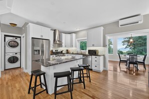 A modern kitchen with a central island, stainless steel appliances, and a view to the outdoors. - Peaceful Cozy Cabin Expansive Views & Sunroom (Waynesville)