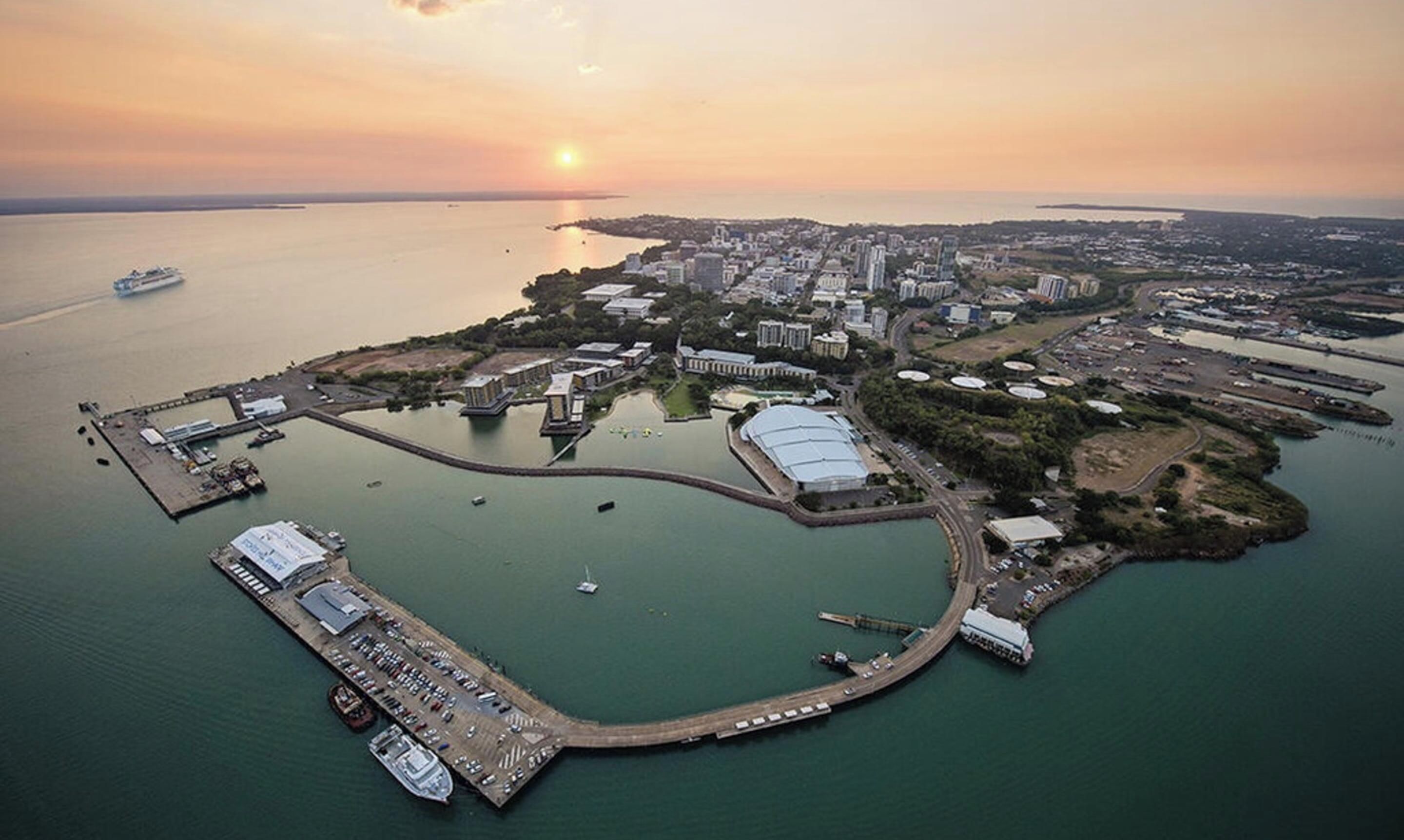Vista aèria d'una ciutat costanera amb un port esportiu, edificis i un vaixell gran amarrat.