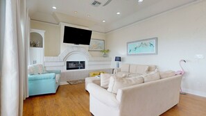 A living room with a fireplace, a television mounted above it, and a sofa. - Sweet Escape: 2  BR, 2.5  BA House in Crystal Beach, Sleeps 7 (Crystal Beach)