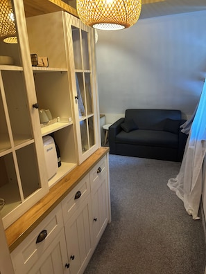 A room with a white cabinet with drawers, a black sofa, and a small table.