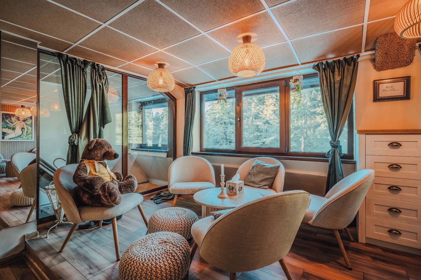 Una habitación acogedora con un ventanal grande, un oso de peluche y una mesa con una vela.