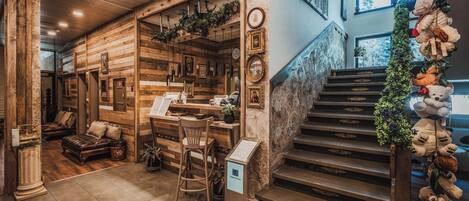 A wooden interior with a staircase, a bar area, and a seating area with leather furniture.