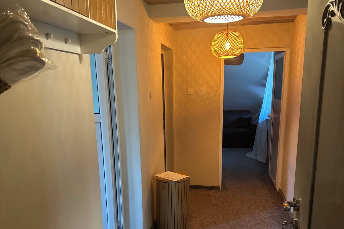 A hallway with a white bench, a trash can, and a hanging light fixture.