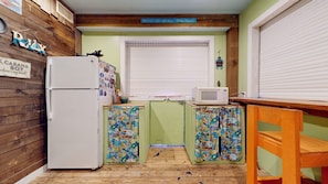 A compact kitchen with a refrigerator, a microwave, and a window with blinds. - Seaside Paradise: 5  BR, 3  BA House in Crystal Beach, Sleeps 16 (Crystal Beach)