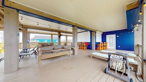 Ein überdachter Außenbereich mit Holzmöbeln, einer Couch und einem Tisch mit Steckdose.