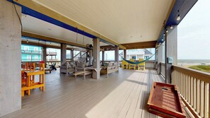 Eine überdachte Terrasse im Freien mit Holzboden, Sitzbereichen und einer Hängematte.