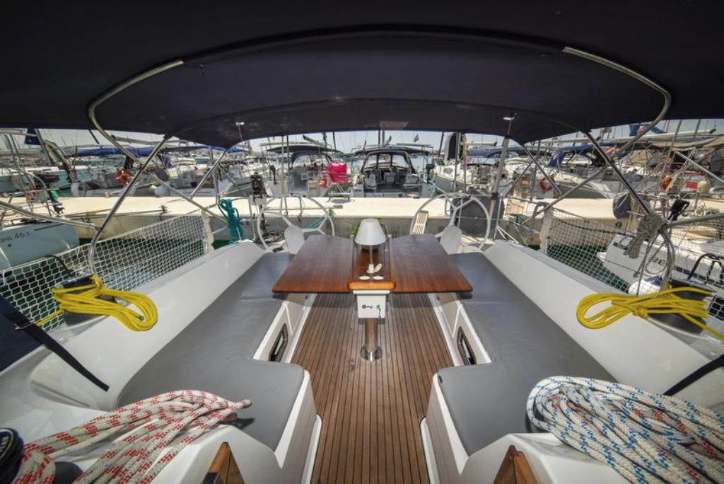 Ein Bootsdeck mit einem zentralen Tisch, Sitzgelegenheiten und Blick auf andere Boote.