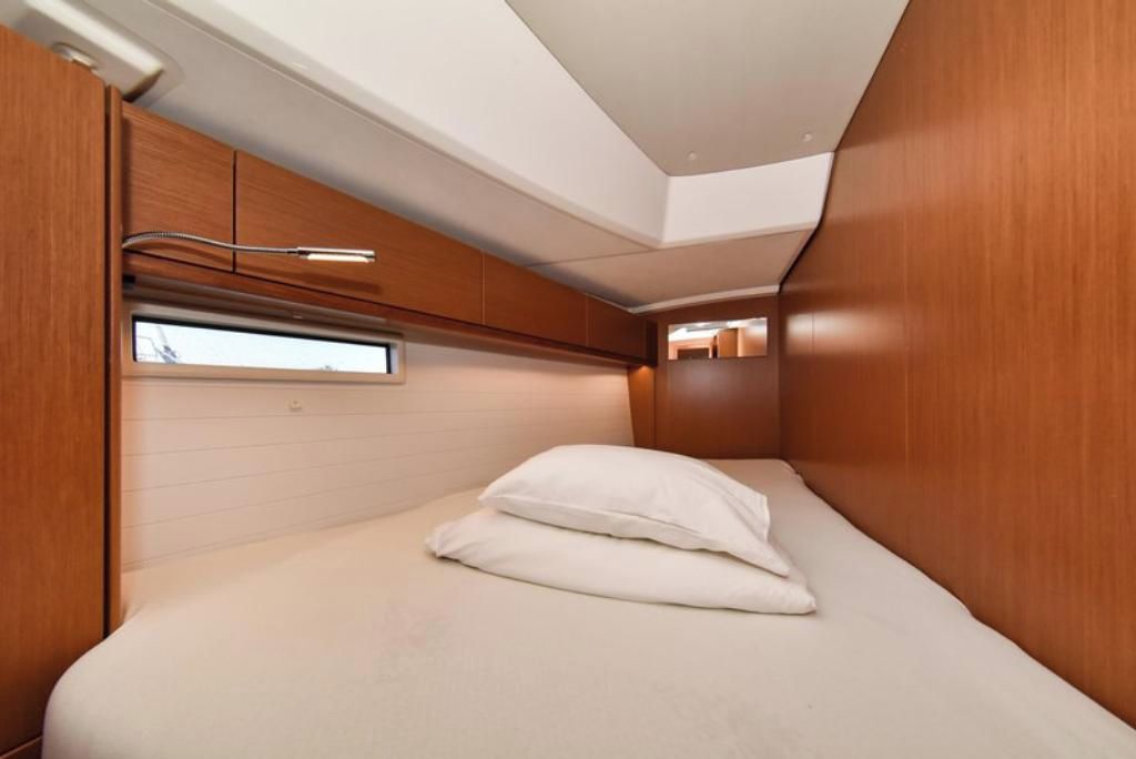 A compact room with a bed, a window, and wooden walls.
