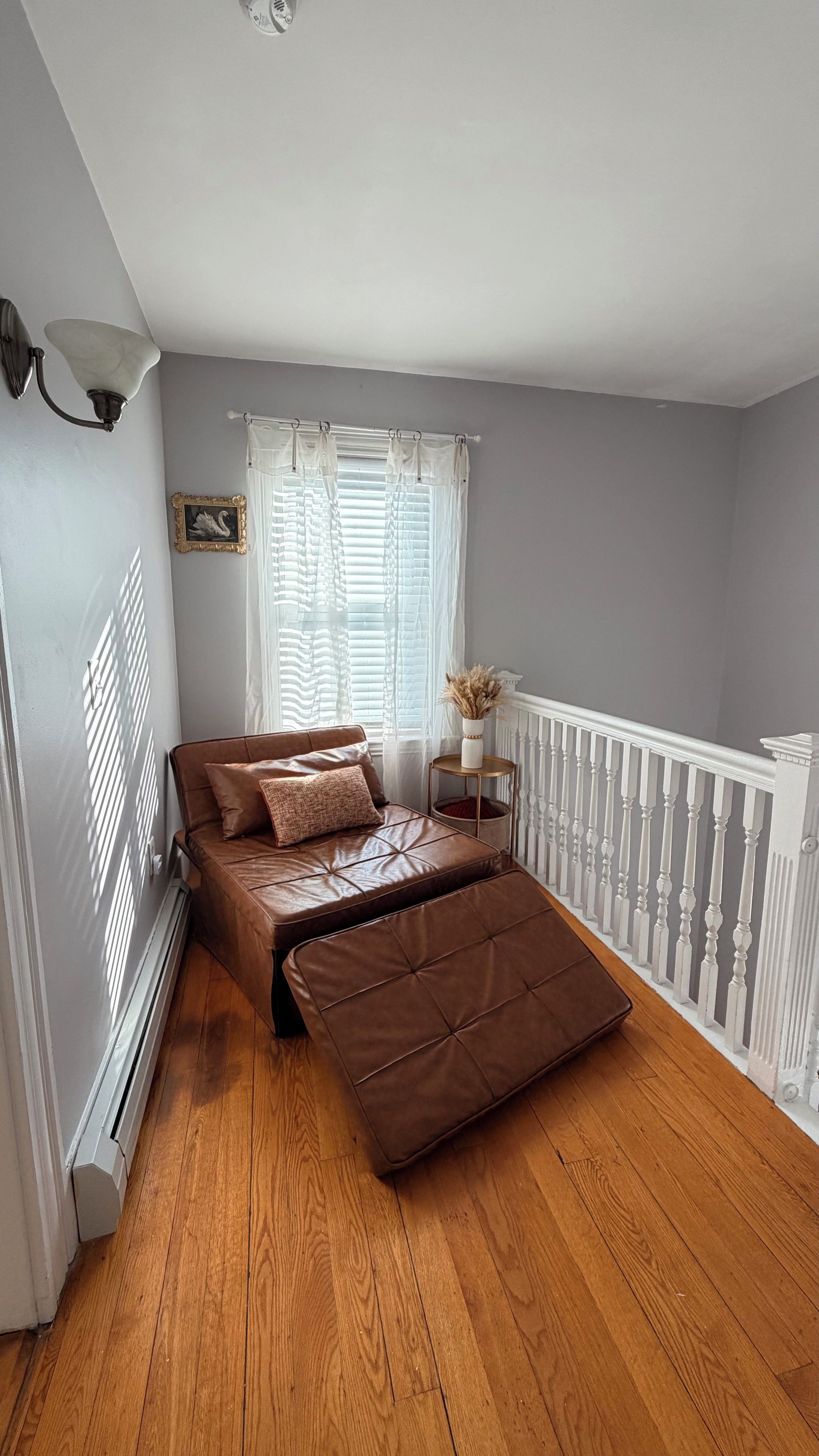 A bedroom with a bed, a window with blinds, a bedside table, and a radiator.