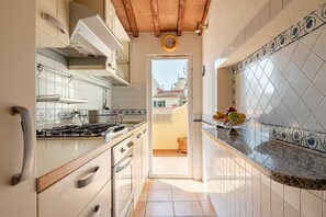 A kitchen with a stove, cabinets, and a fruit bowl on the counter. - Attic Piazza Santa Croce with living terrace (FIRENZE)