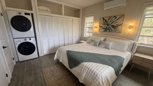 Quarto com cama, máquina de lavar, armário e janela.