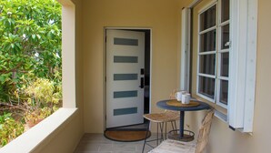 Uma pequena área externa com mesa, cadeiras, uma porta e uma janela com persianas.