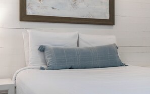 A bed with white linens and a single blue pillow with a textured pattern. - Southern Yankee | Cozy Rosemary Beach Condo (Rosemary Beach)