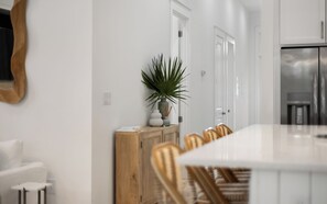 A modern kitchen with a central island, wooden chairs, and a potted plant. - Salt and Pine | Golf Cart, Pool, Bikes (Santa Rosa Beach)