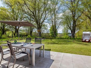 Eine Terrasse im Freien mit Tisch, Stühlen, einem Sonnenschirm und einer Liege.