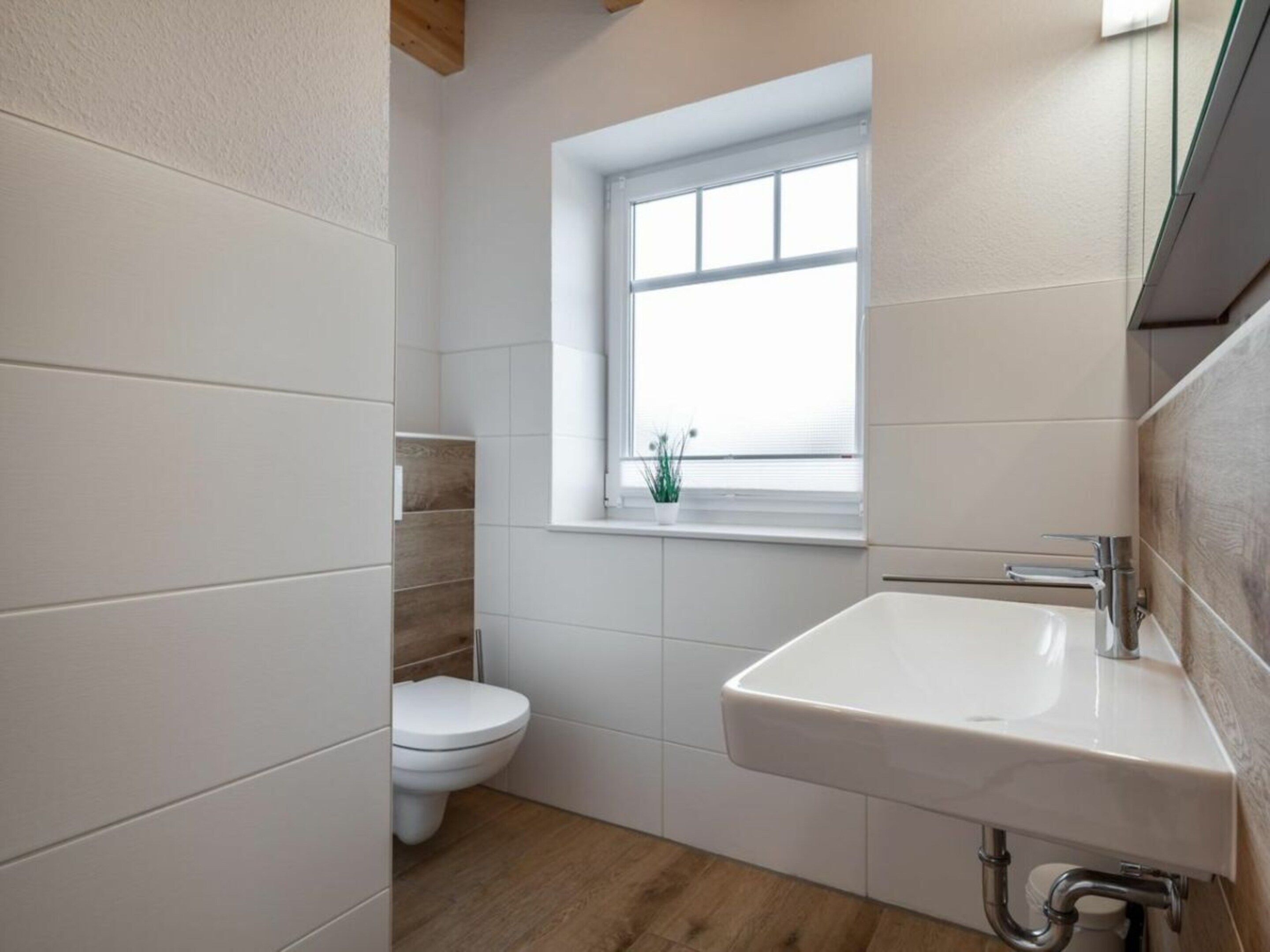 Et badeværelse med toilet, et vindue og en vask.