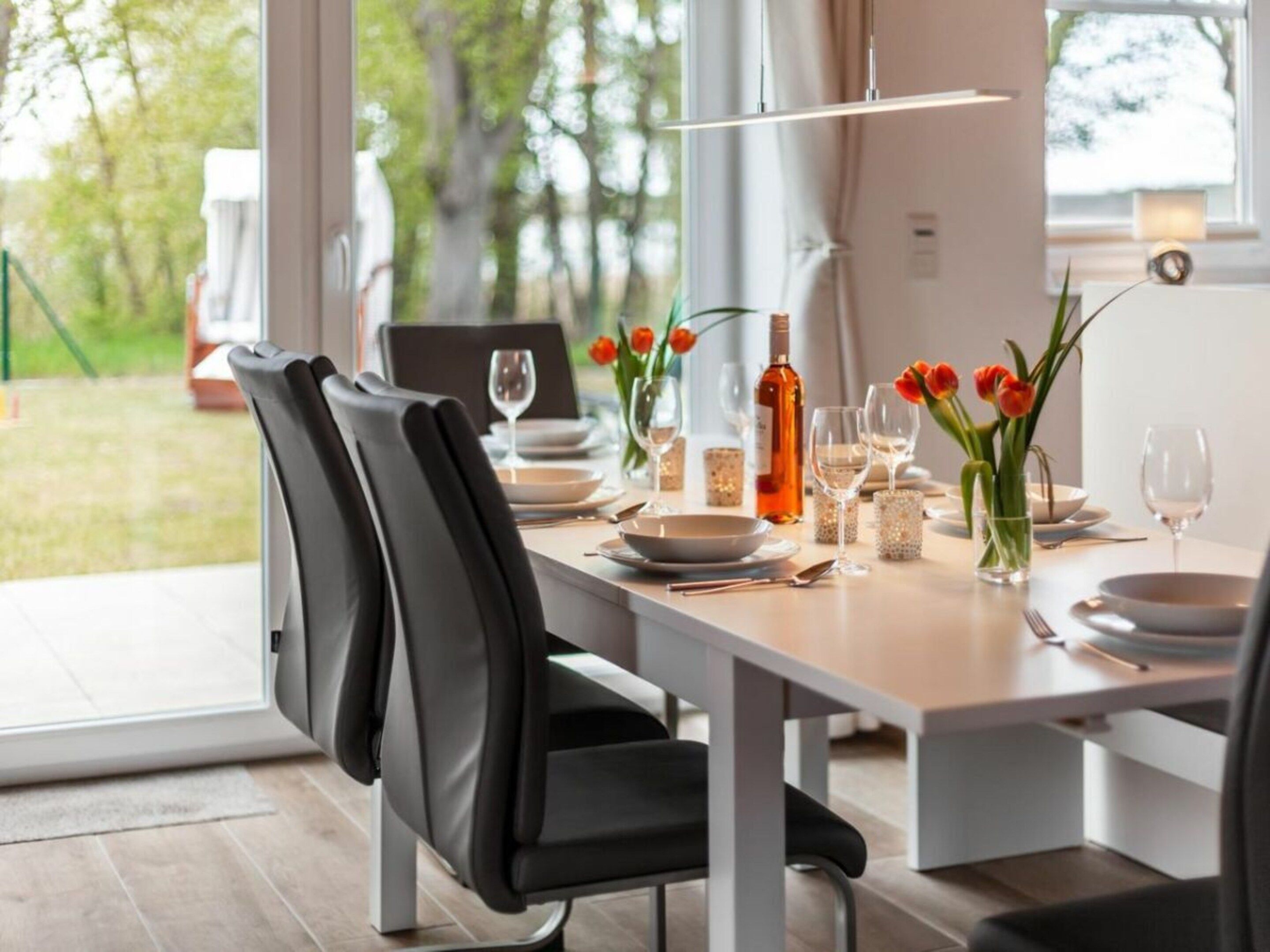 Ein Essbereich mit Tisch für zwei Personen, Stühlen und Blick ins Freie.