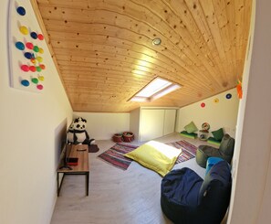 A cozy room with a sloped ceiling, a bed, a desk, and a panda plush toy. - Sunset House Meco pôr do Sol & Praia a 1500 m (Alfarim-sesimbra)