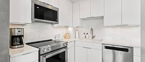 A modern kitchen with stainless steel appliances, white cabinetry, and a built-in microwave.