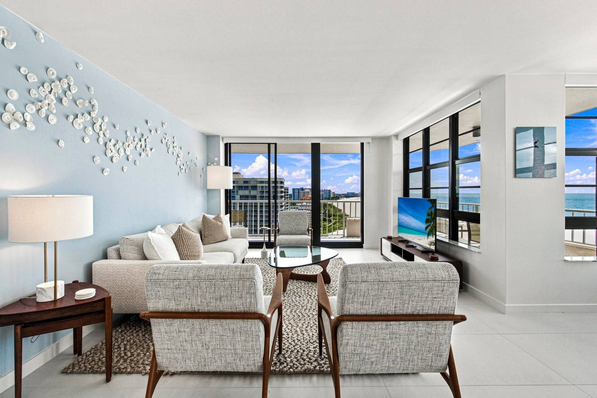 A modern living room with a sofa, armchairs, a coffee table, and a TV.