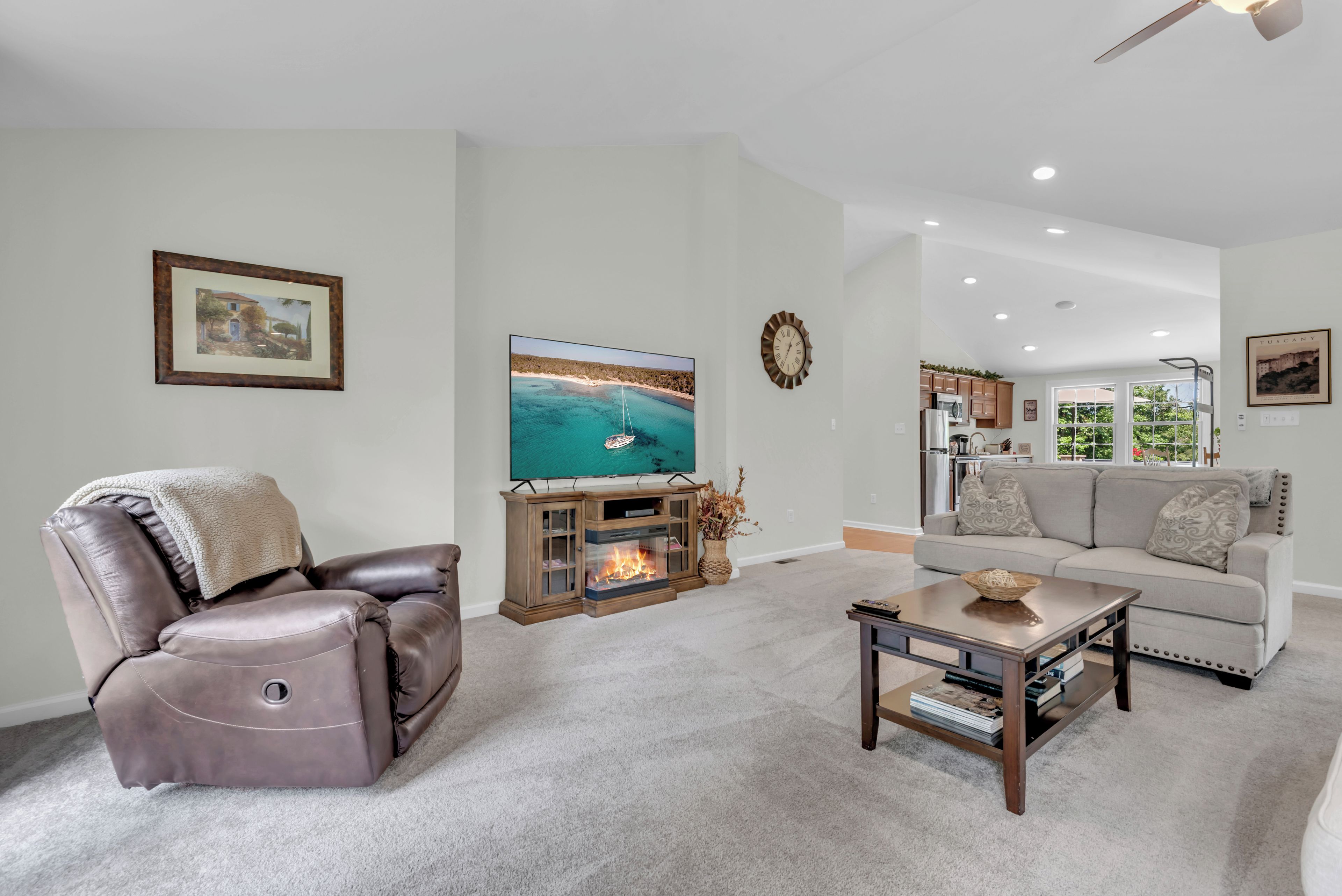 A living room with a leather recliner, a flat-screen TV, a fireplace, a sofa, and a coffee table.