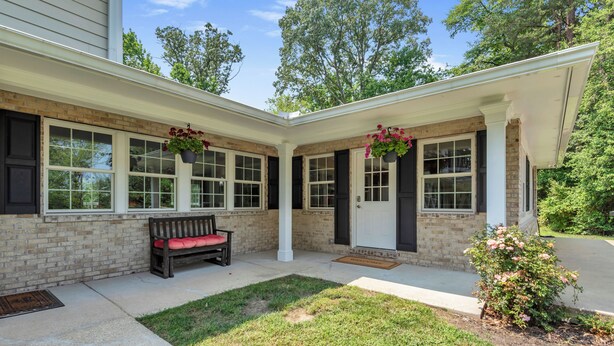 A house with a brick exterior, a front porch with a bench, and hanging flower baskets. - The Harness Creek Retreat in Annapolis (Annapolis)