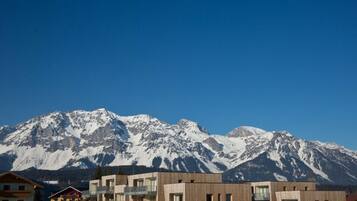 A modern building complex with multiple balconies and a mountain backdrop.