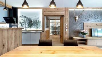 A modern kitchen with wooden cabinets, a dining area with a large wooden table, and pendant lighting.