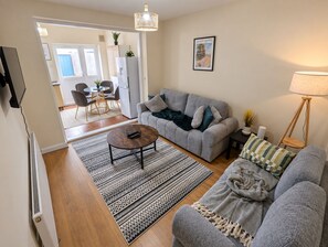 Ett vardagsrum med en grå soffa, ett soffbord och en mönstrad matta.