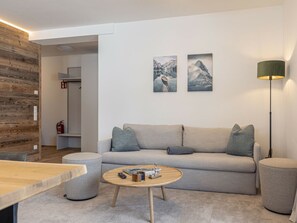 A modern living room with a sofa, coffee table, and artwork on the wall. - Apartment With 1 Bedroom (Sankt Martin am Tennengebirge)