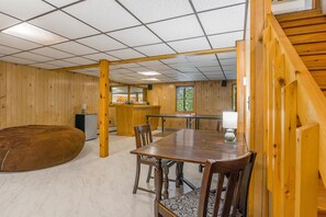 Ein Holzinnenraum mit Esstisch, Stühlen, einer Couch und einer Küchenzeile.