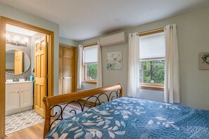 Ein Schlafzimmer mit einem Bett, einem Kleiderschrank, einem Spiegel und einem fenster mit Vorhängen.