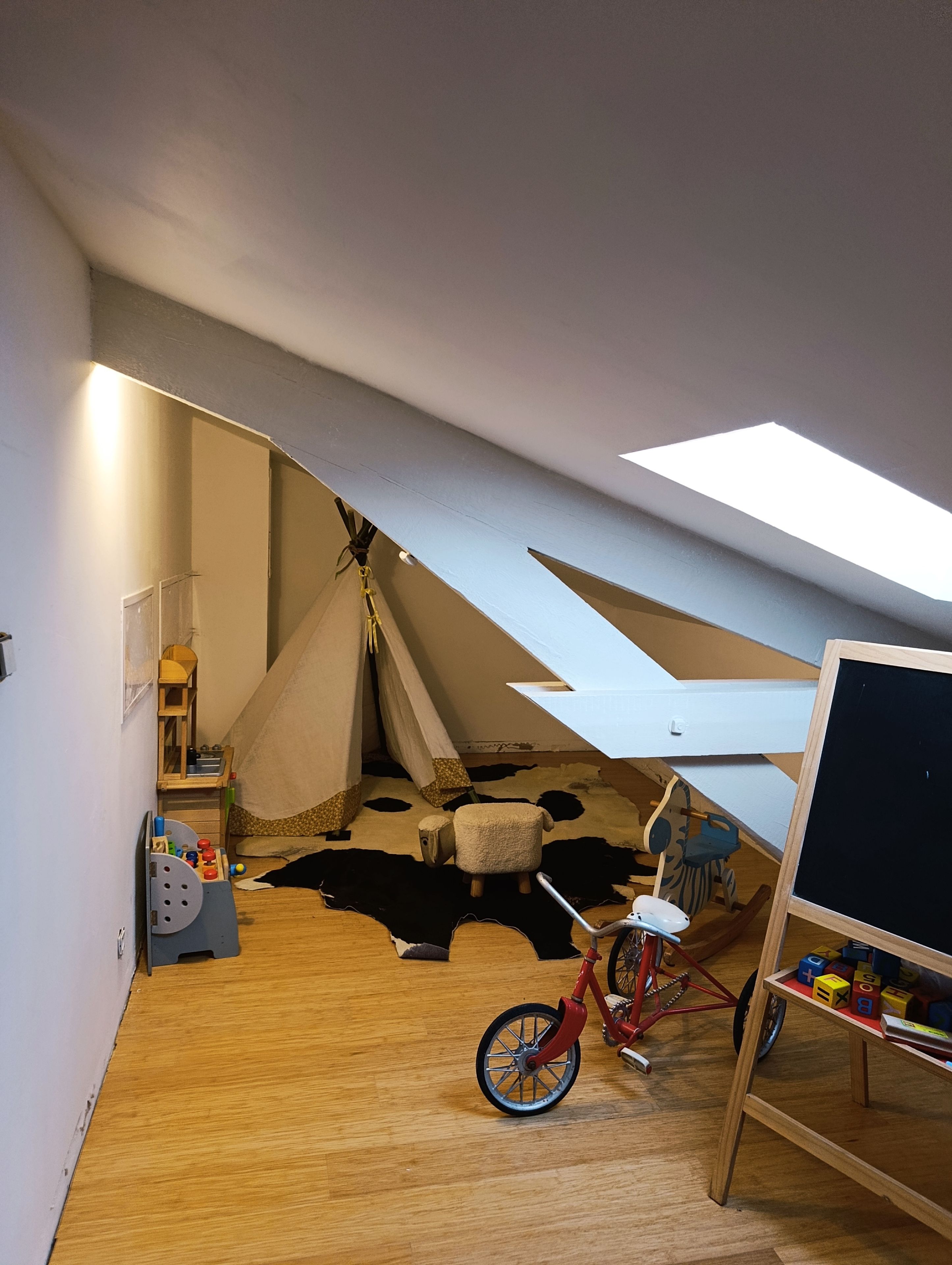 A child's playroom with a tent, a rocking horse, and a red bicycle.
