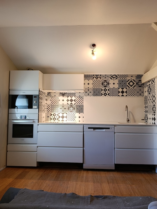 A compact kitchen with a Bosch oven, dishwasher, and a patterned backsplash.
