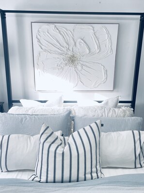 Ein Bett mit gestreiften Kissen und einem großen Blumenbild darüber.