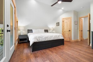 A bedroom with a bed, nightstands, a ceiling fan, and wooden doors. - Blackberry Woods | A Peaceful Maine Retreat in Hope (Hope)