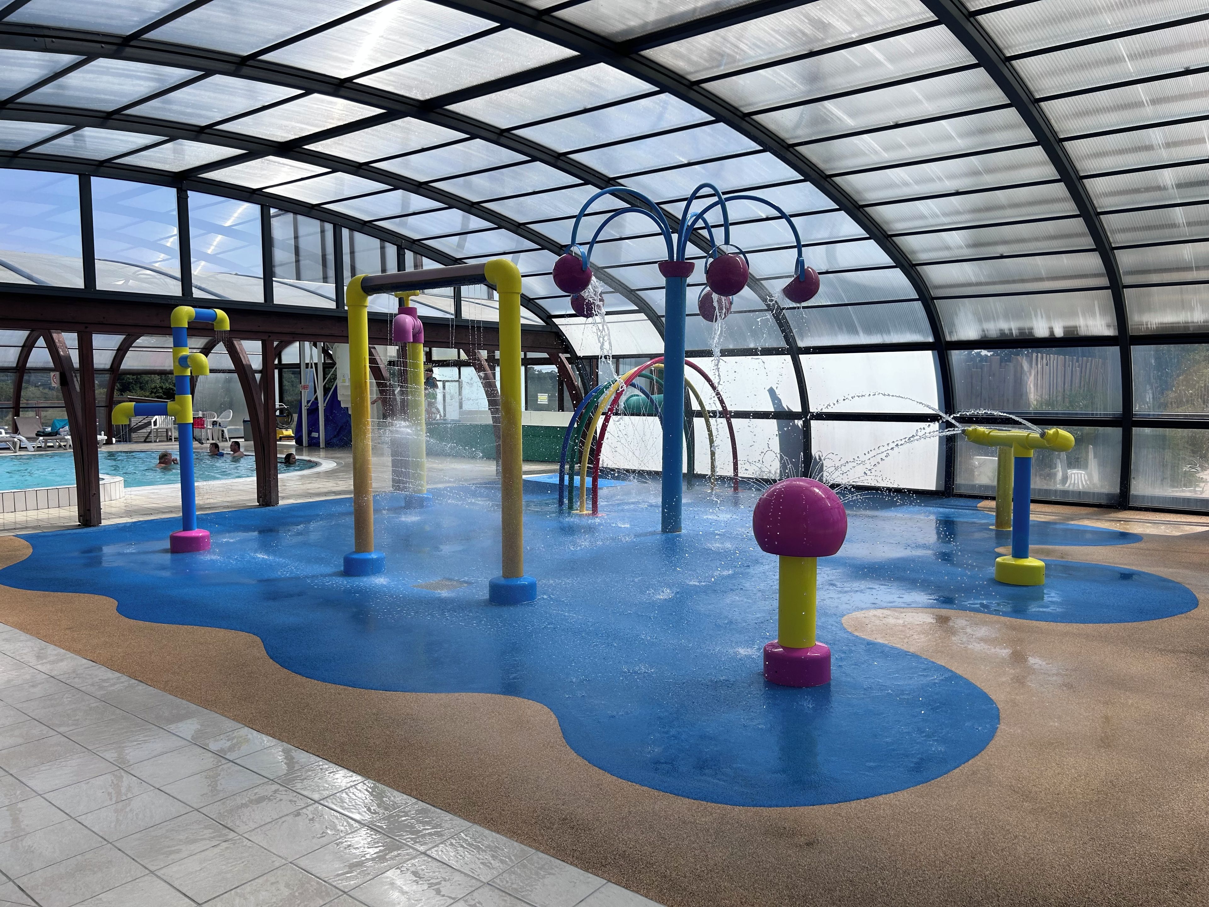 An indoor water play area with multiple water jets and colorful play structures.