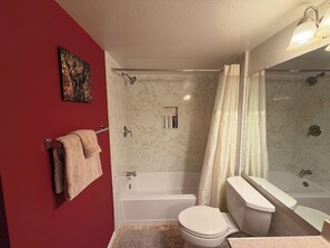 Ein Badezimmer mit Badewanne, Toilette und Duschbereich.