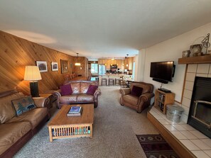 Ein gemütliches Wohnzimmer mit Holzwand, Ledersofas, einem Couchtisch und einem Kamin.