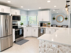 Una cocina moderna con electrodomésticos de acero inoxidable, armarios blancos y una pared de acento de piedra.