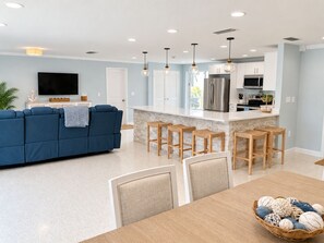 A modern kitchen with a central island, bar stools, and a dining table with chairs. - 3/2.5 Canal Front Home, Private Pool, Dock on LBK (Longboat Key)