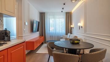Una habitación de hotel moderna con comedor, sofá y televisor.