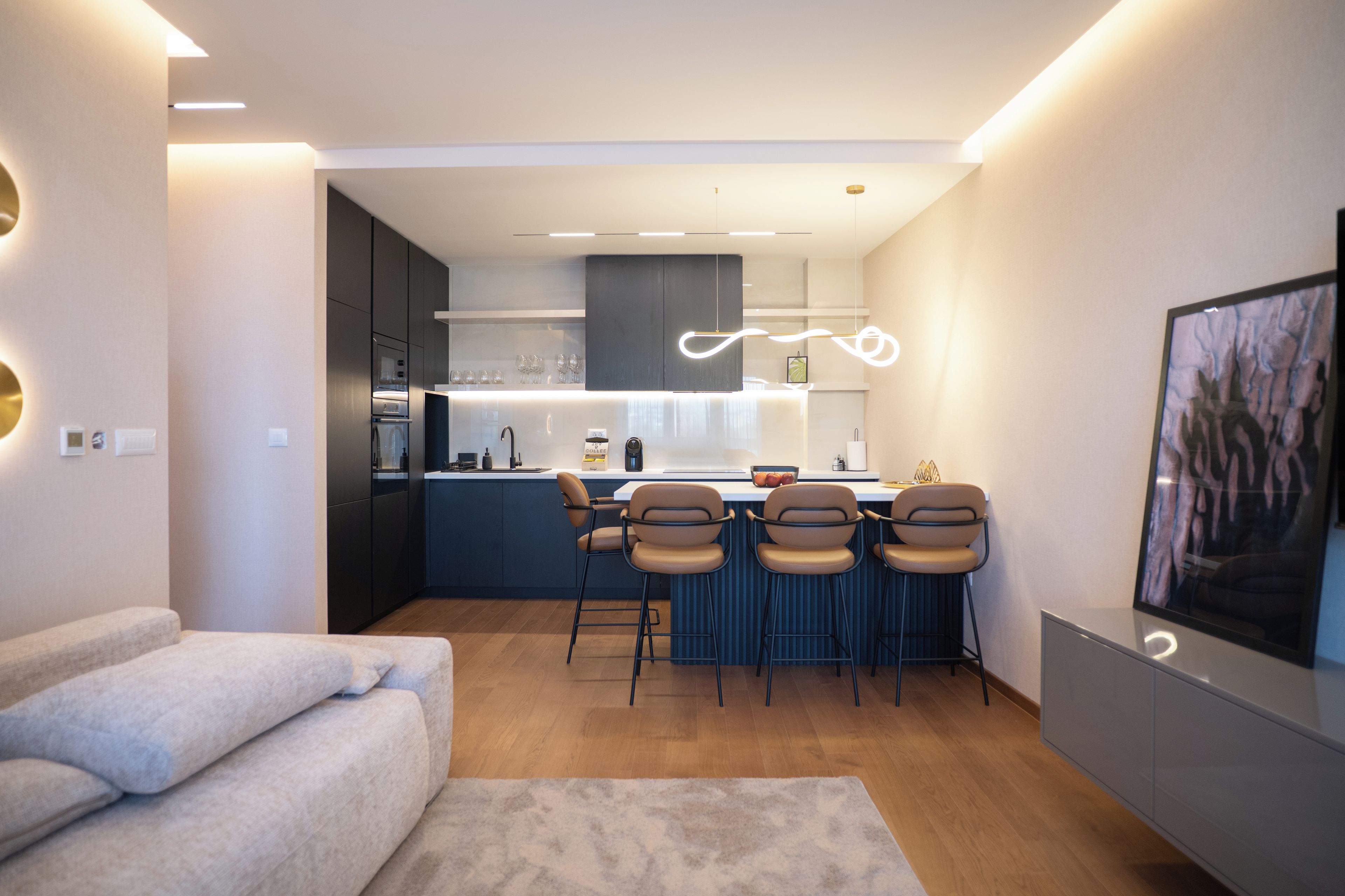 Una cocina moderna con una isla central, taburetes de bar y una zona de comedor.