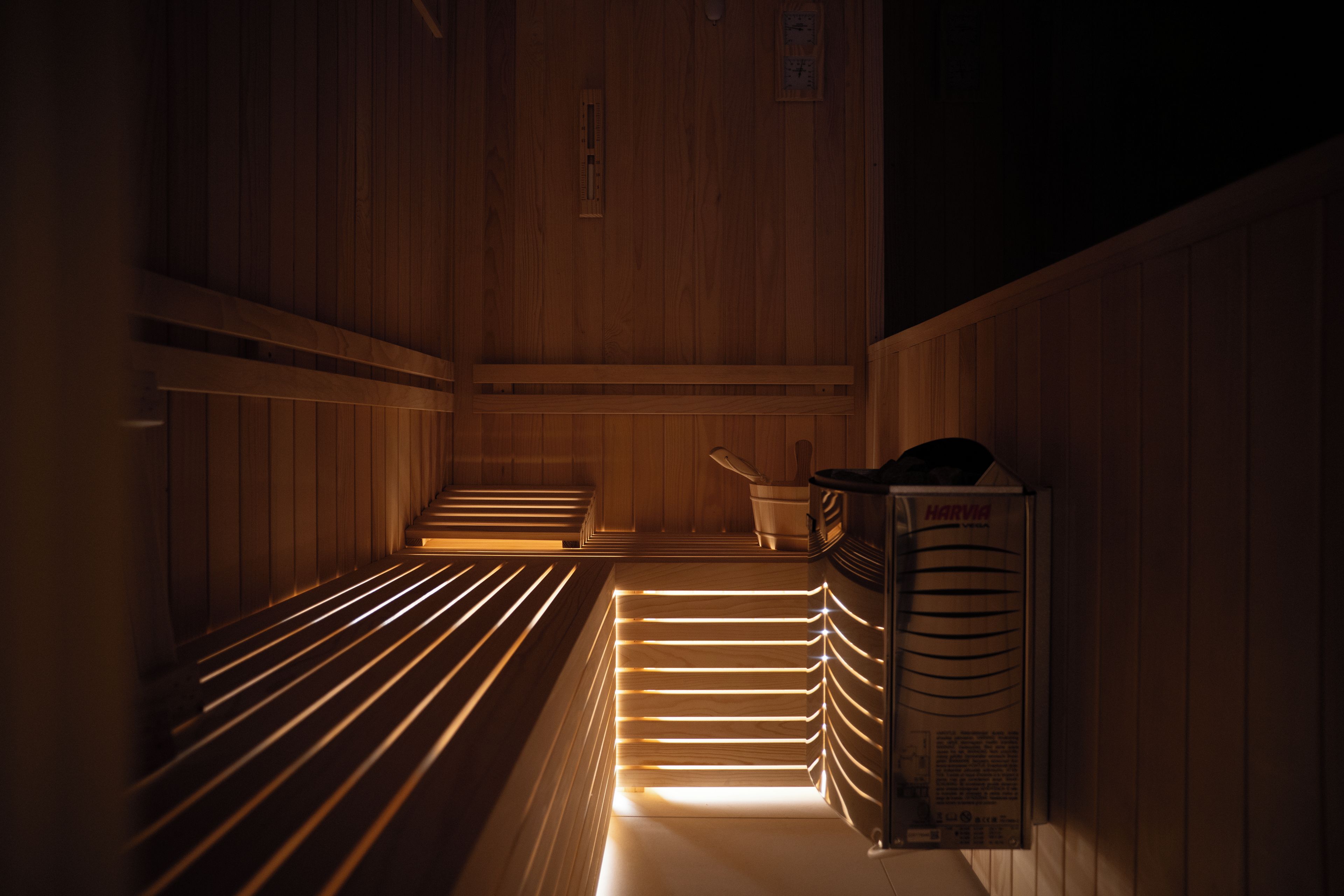 A sauna with wooden benches and a Harvia sauna heater.