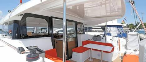 A boat deck with a covered seating area, a table, and a mast.